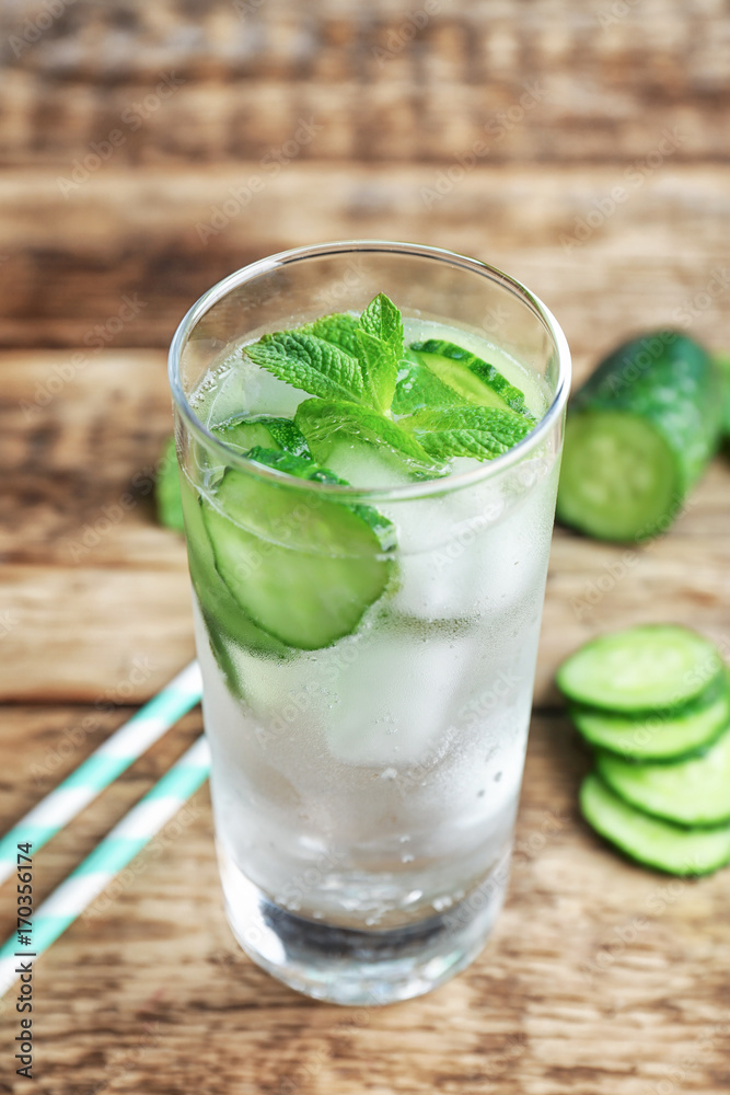 Delicious refreshing water with mint and cucumber in glass on wooden table Delicious refreshing water with mint and cucumber in glass on wooden table