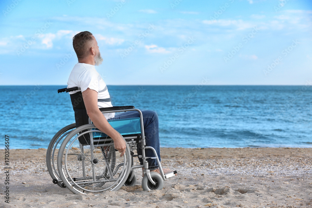 Elderly man in wheelchair on sea coast