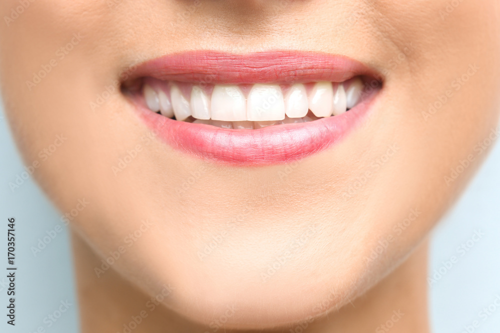 Fototapeta premium Young beautiful woman with healthy teeth smiling on light background, close up