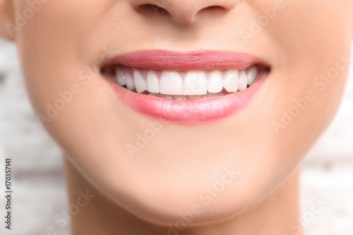Young beautiful woman with healthy teeth smiling on light background, close up photo