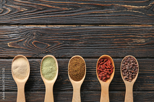 Composition with assortment of superfood products in wooden spoons on table, top view