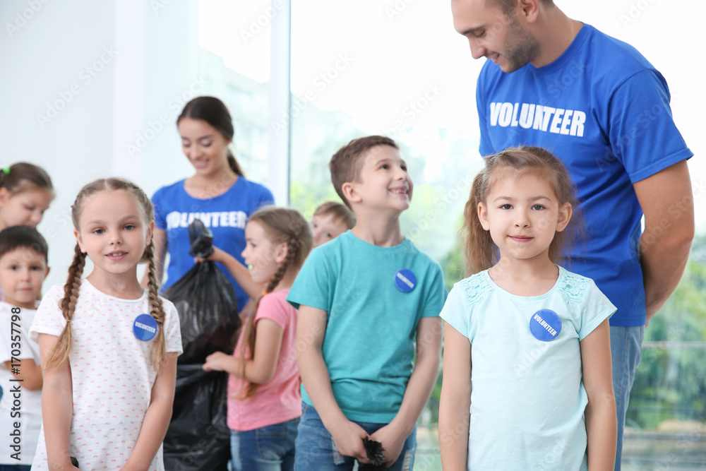 Happy volunteers and children with garbage bags indoors Happy volunteers and children with garbage bags indoors