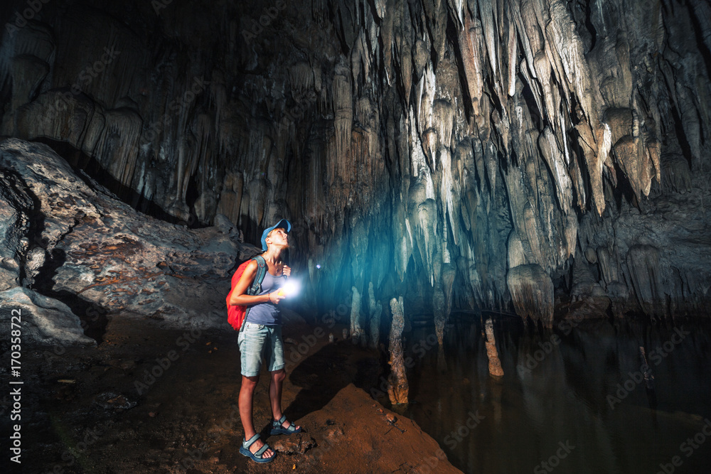 Young woman explores cave with stalagmites and stalactites