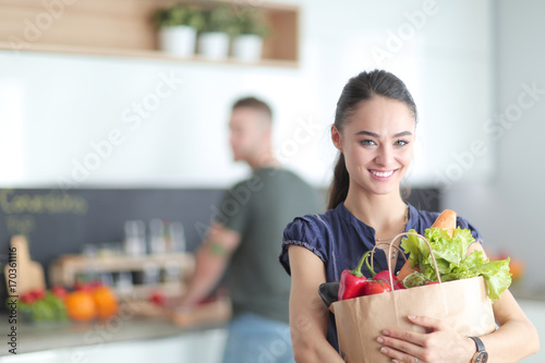 Young couple in the kitchen , woman with a bag of groceries shopping photo