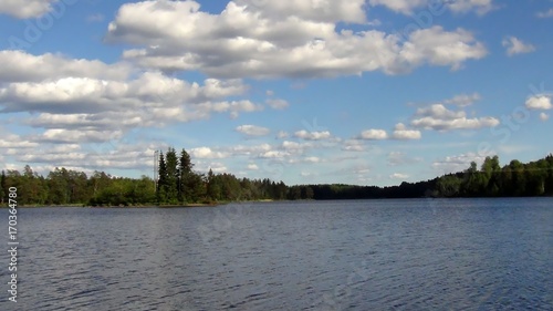 Wonderful view of blue sky with white clouds and still lake on a summer day © Alex