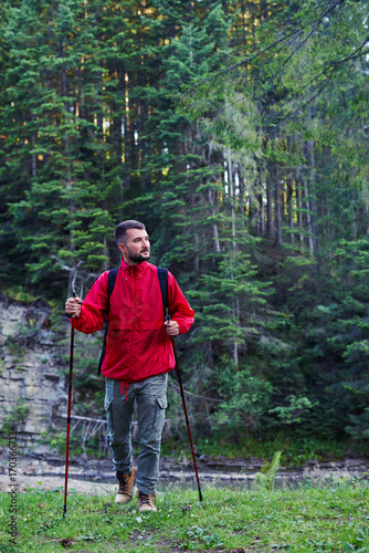 Man in hiking outfit with poles in mountains
