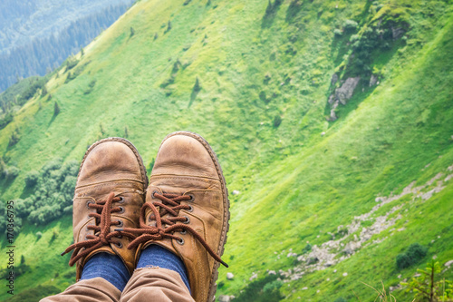 Travel, trekking. Foot traveler in shoes, against the backdrop of mountains. Horizontal frame