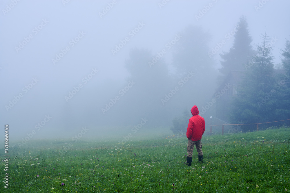 Tourist in waterproof jacket in fog