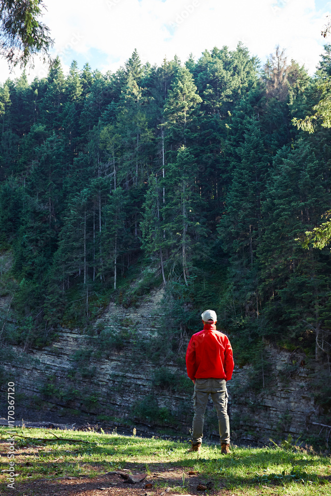 Obraz premium Man hiker in waterproof jacket admiring the cliff