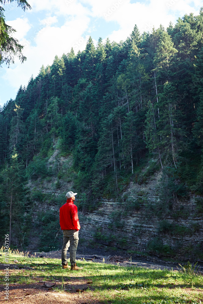 Hiker observing stone cliff with forest