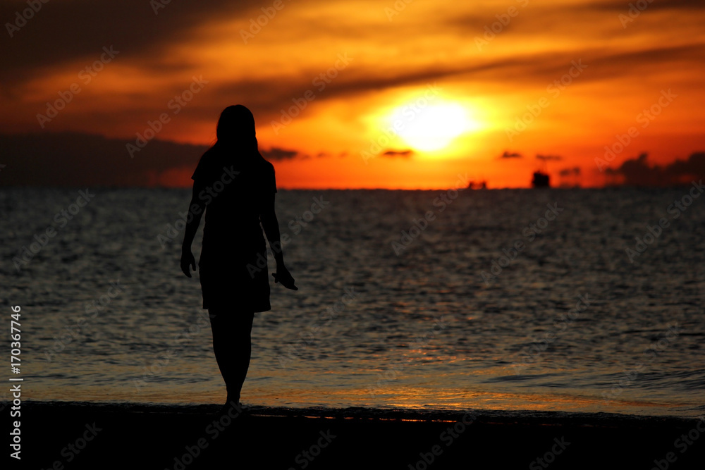 silhouette of woman walking on the beach