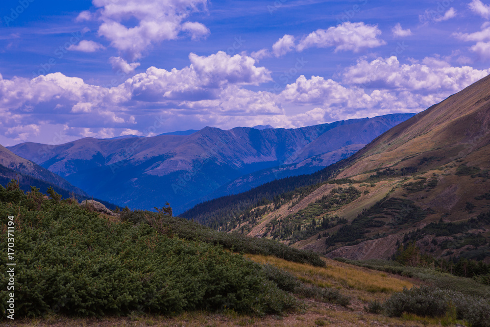 Fototapeta premium View on a mountains and hills with green grass on it and blue sky. Colorado. Mountain Evans. Denver. USA