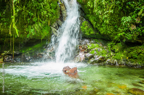 Beautiful small waterfall in green forest with stones in river at Mindo photo