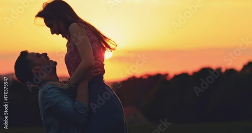 Young Couple Kissing at Sunset. SLOW MOTION 4K. Romantic man embracing his beloved woman and they share a kiss. Love and affection. Cinematic backlit shot, Lens Flare.