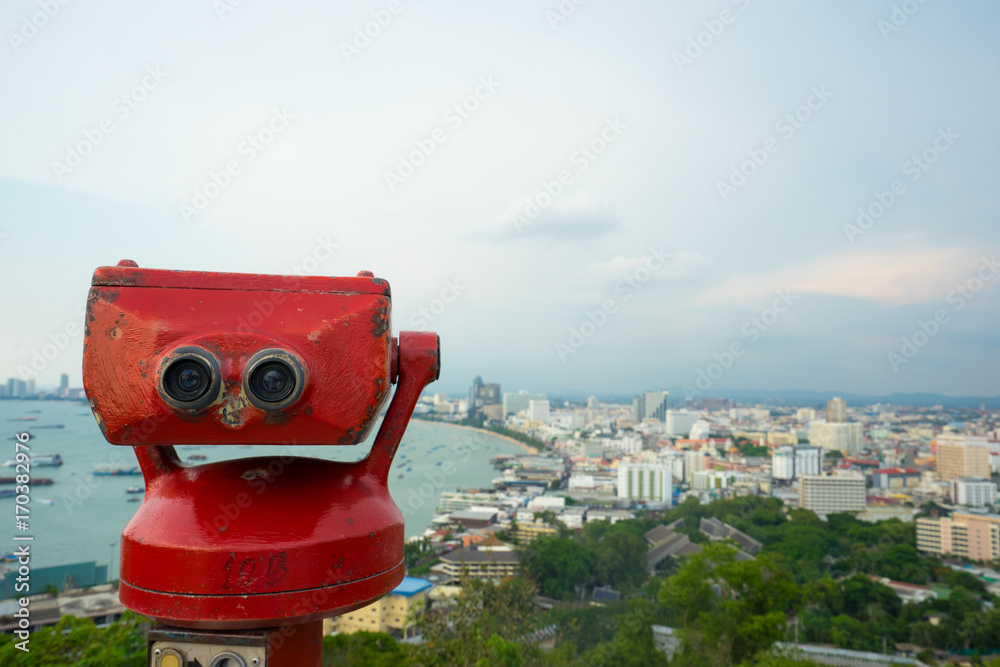 Coin Operated Binocular viewer next to the waterside promenade in Pattaya (Thailand) looking out to the Bay and city. Landscape with beautiful cloudy sky, sea.