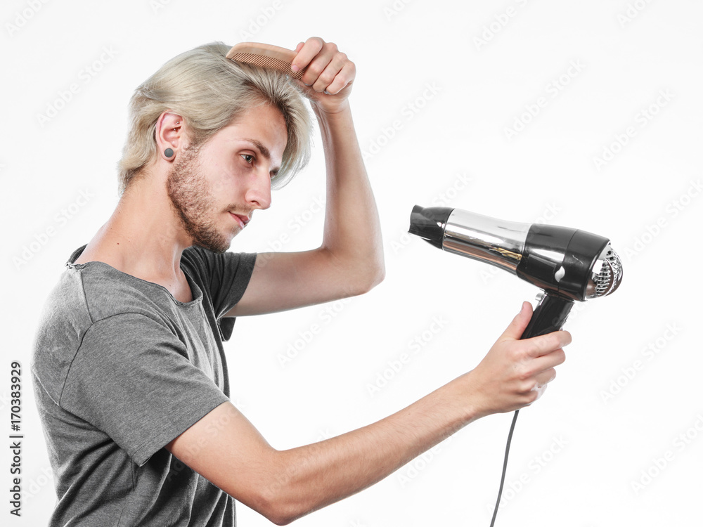 Young man drying hair with hairdryer