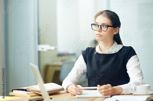 Serious office worker contemplating or waiting for end of working day