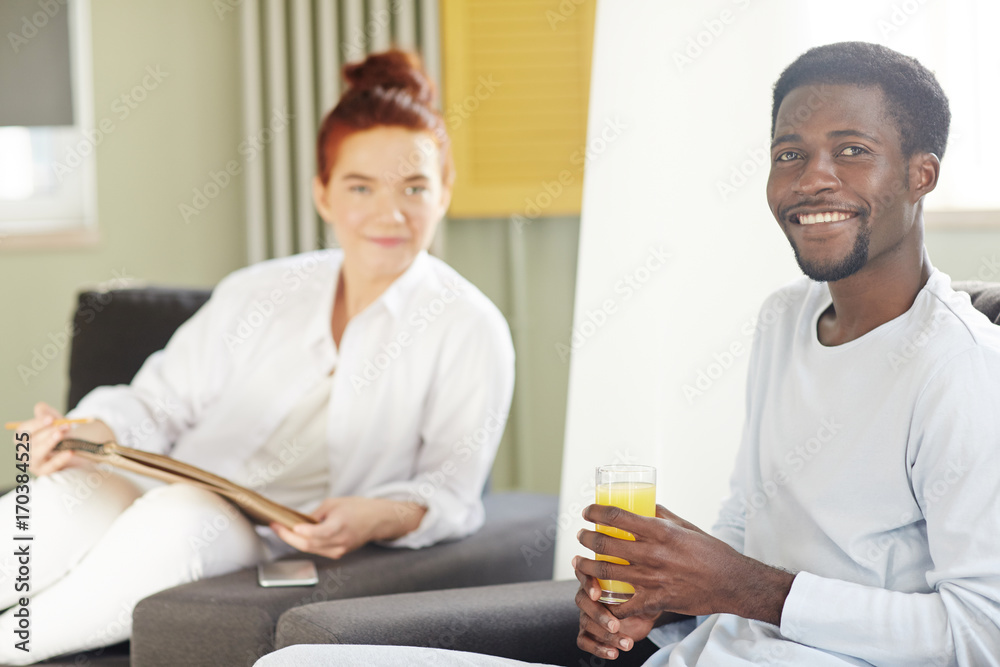 Group portrait of loving multi-ethnic couple looking at camera with wide smiles while relaxing at cozy living room Group portrait of loving multi-ethnic couple looking at camera with wide smiles while relaxing at cozy living room