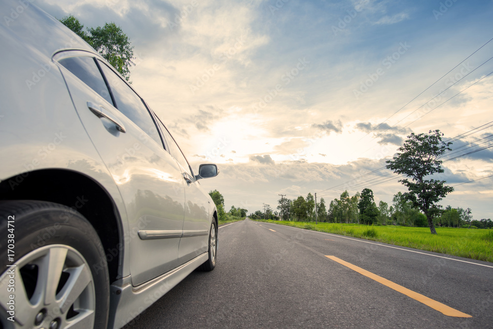 Fototapeta premium Car on road with green meadow and sunset background in Thailand
