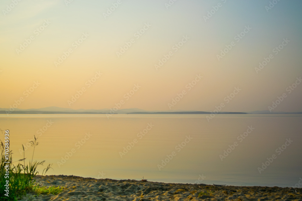Golden sunset at a shore of a lake with silhouette of plants, Uveldy, the Ural, Russia