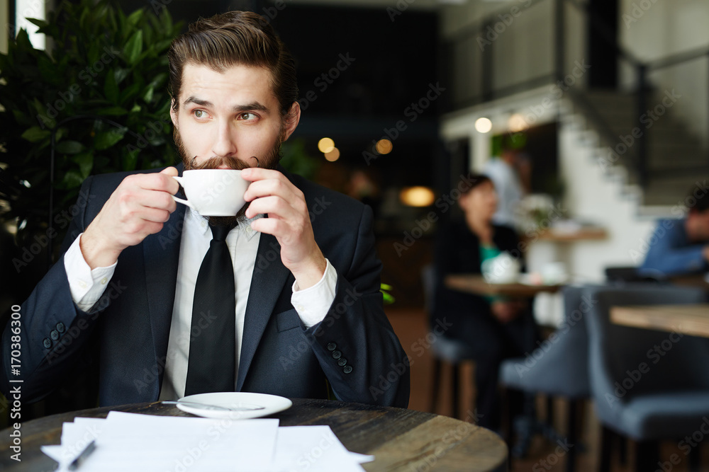 Young entrepreneur having tea or coffee in cafe at break Young entrepreneur having tea or coffee in cafe at break