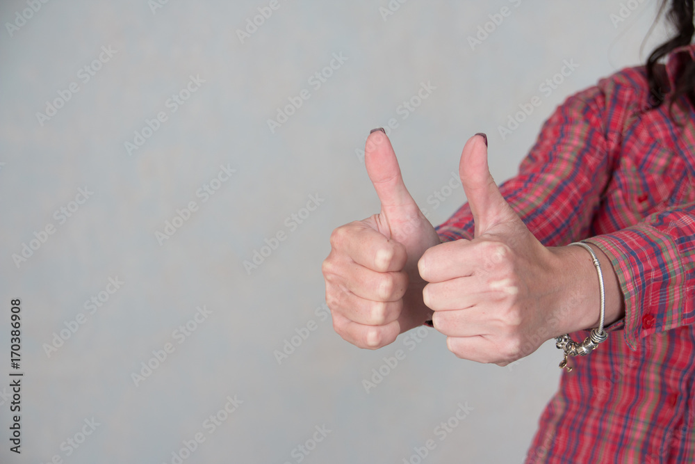 woman showing thumbs up sign in office with copy space.girl dressed in casual clothing. Focus at hands. she giving thumb up as sign of success on gray background. customers feedback concept woman showing thumbs up sign in office with copy space.girl dressed in casual clothing. Focus at hands. she giving thumb up as sign of success on gray background. customers feedback concept