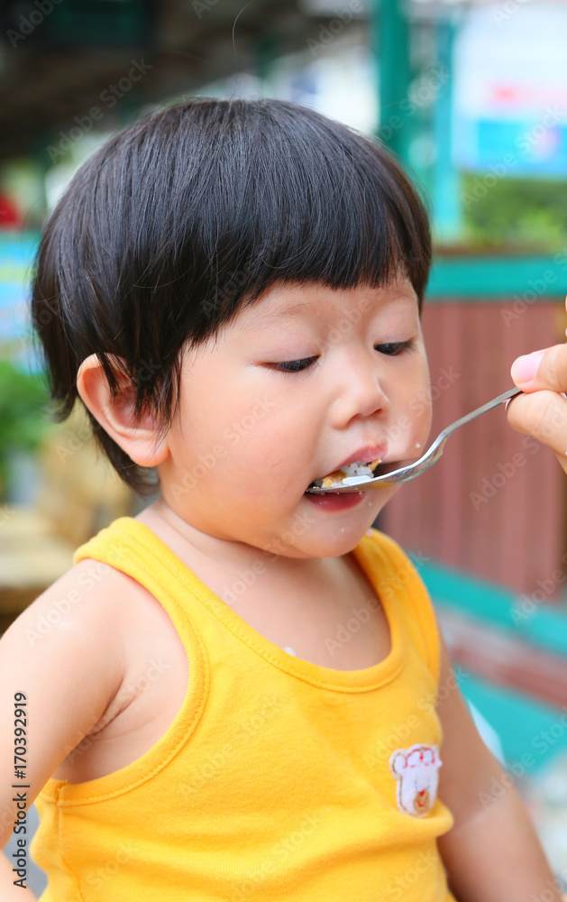 Little Asian baby eating rice by stainless spoon. Little Asian baby eating rice by stainless spoon.
