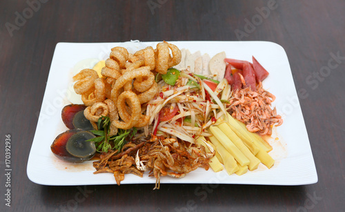Thai spicy papaya salad serve with preserved egg, shoot, pork rind and crab.