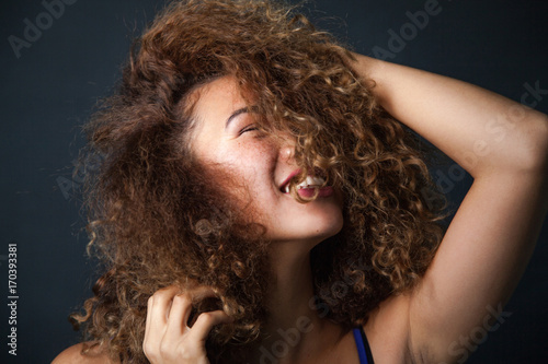 Portrait of a curly woman with freckles on dark background. Smiling girl.