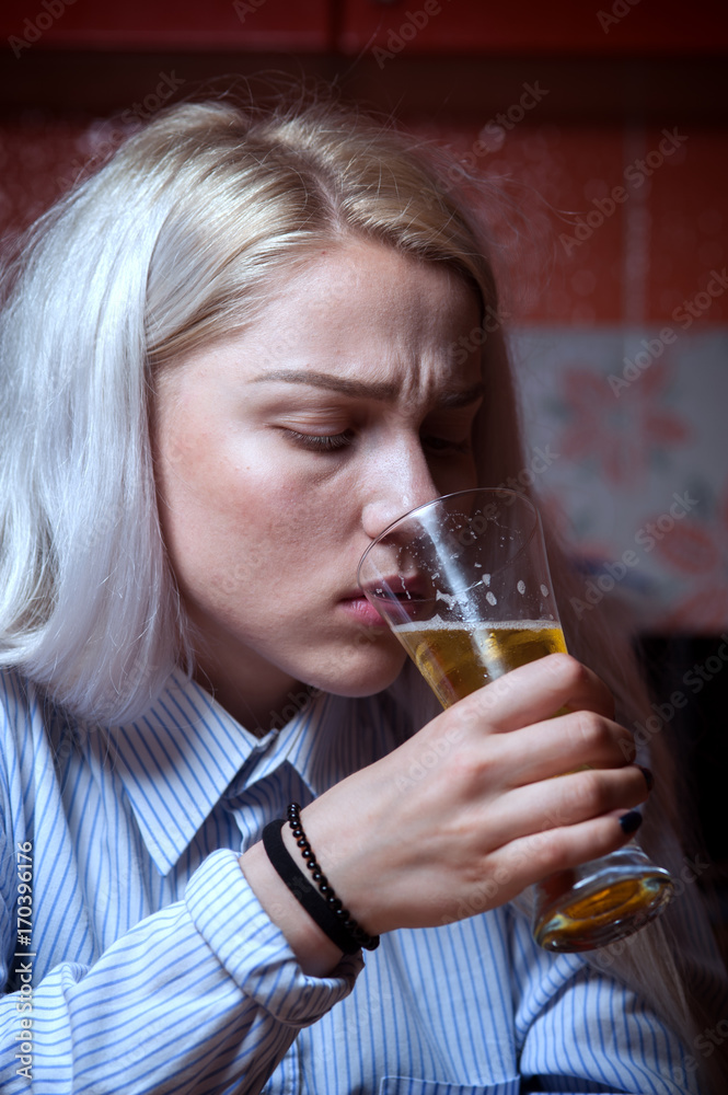 Sad depressed female drinking beer alone at home Sad depressed female drinking beer alone at home