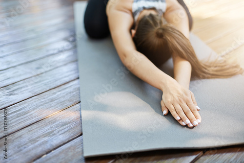Close up of hands doing yoga or pilates laying on a grey mat in a temple or a backyard. photo