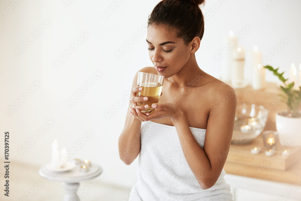 © Cookie Studio - Attractive african girl drinking green tea resting in spa salon. Closed eyes. © Cookie Studio - Attractive african girl drinking green tea resting in spa salon. Closed eyes.
