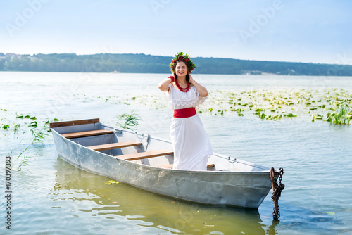 beautiful girl in national clothes in a boat on a pond © RomanR