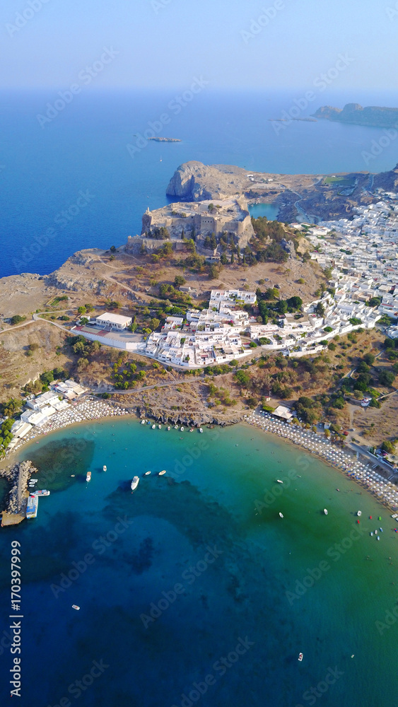 Aerial drone photo of famous beach of Lindos with turquoise waters and iconic ancient Acropolis - village of Lindos, Rodos island, Aegean, Dodecanese, Greece