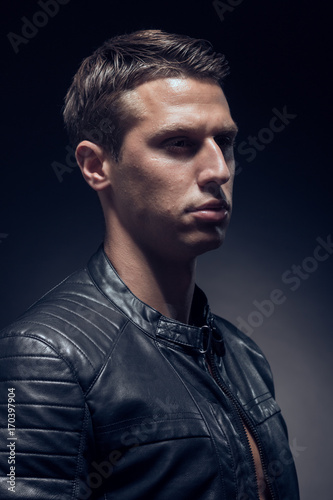 head and shoulders shot, one young adult man Caucasian, black background, studio, head headshot face, leather jacket, portrait