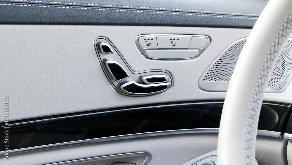 Door handle with Power seat conrtol buttons of a luxury passenger car. White leather interior of the luxury modern car. Modern car interior details