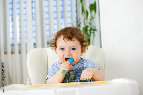 Cute baby boy eating by himself