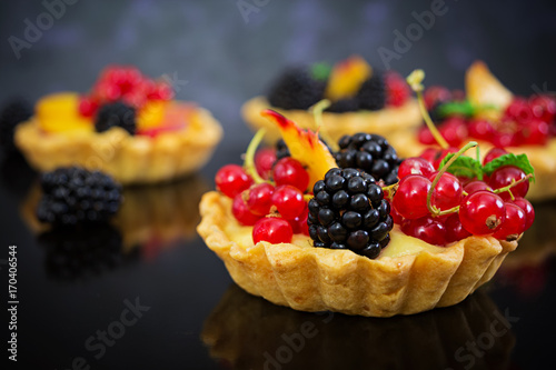 Tartlets with different berries on dark background