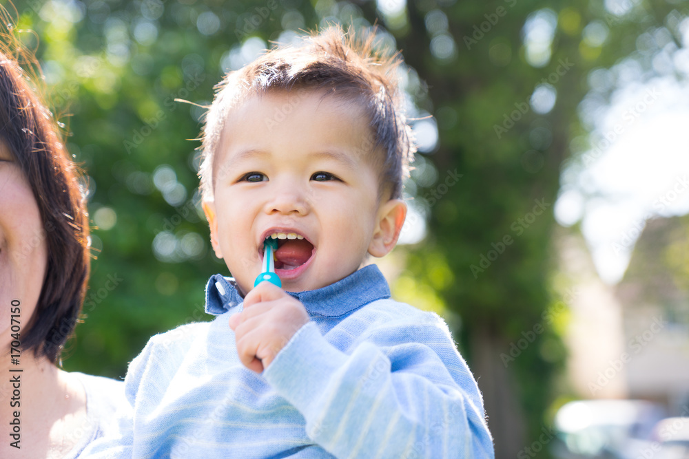 Asian baby uses toothbrush in the park, summer time Asian baby uses toothbrush in the park, summer time