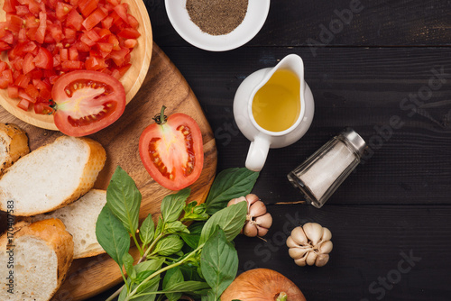 Preparing delicious Italian tomato bruschetta with chopped vegetables, herbs and oil photo