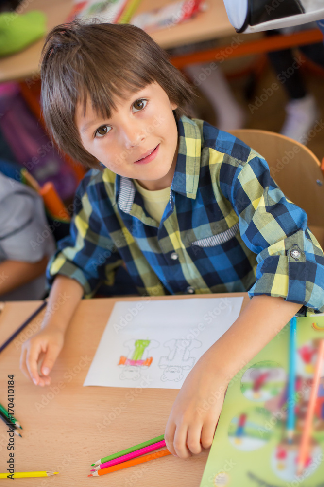 Young first grade student sitting at desk on his first day at school Young first grade student sitting at desk on his first day at school