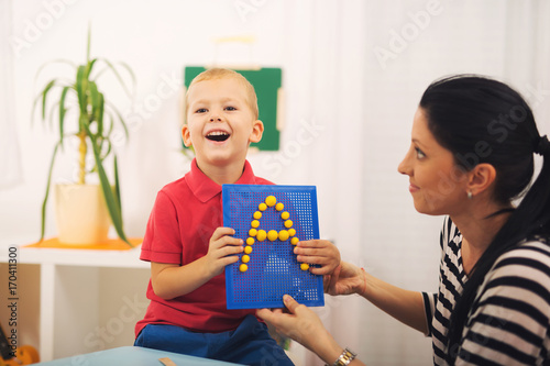 Little boy during lesson with his speech therapist. Learning through fun and play photo