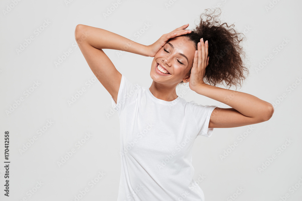 Fototapeta premium Pleased woman with closed eyes holding hands on head