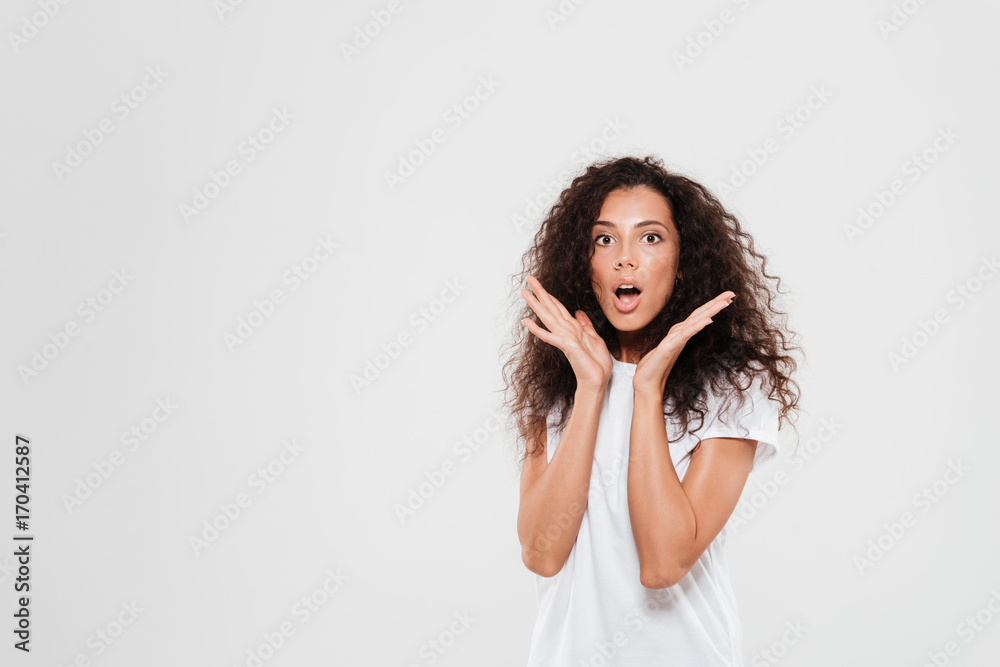 Shocked curly woman holding hands near the head Shocked curly woman holding hands near the head