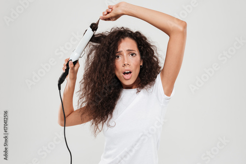 Принти на полотні Surprised young brunette woman straighten her hair