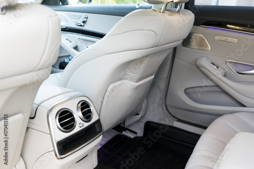 White leather interior of the luxury modern car. Leather comfortable white seats and multimedia. exclusive wood and metal decoration. Modern car interior details. © Aleksei