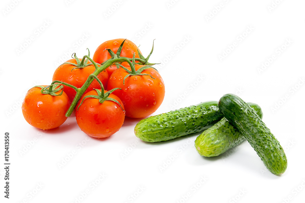 Bunch of red tomatoes and several green cucumbers on the white background.