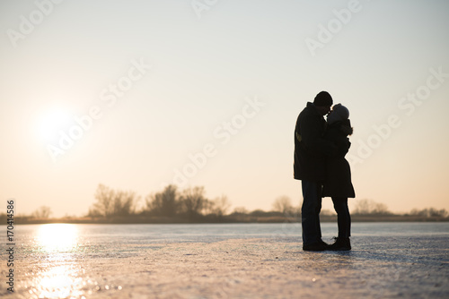 Couple kissing and hugging on frozen lake