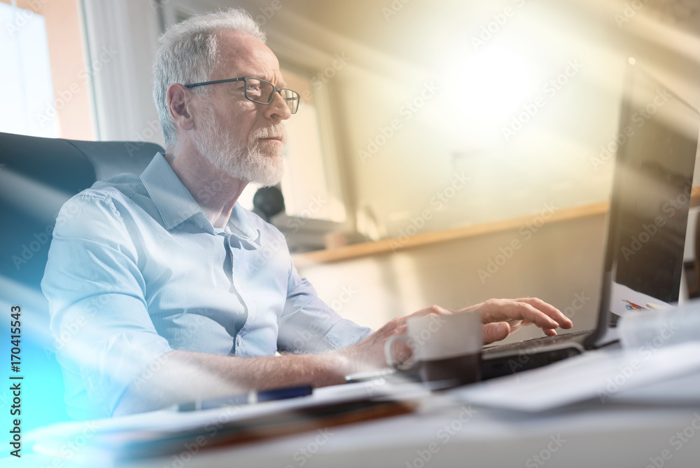 Portrait of senior businessman working on laptop, light effect