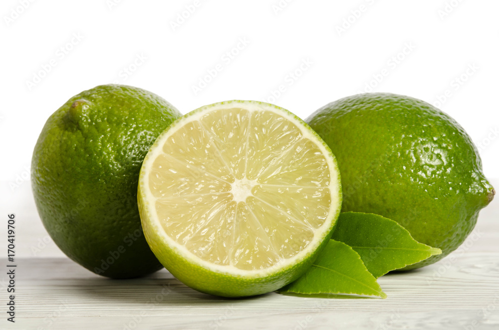 two lemons with half of  juicy lime on a wooden table